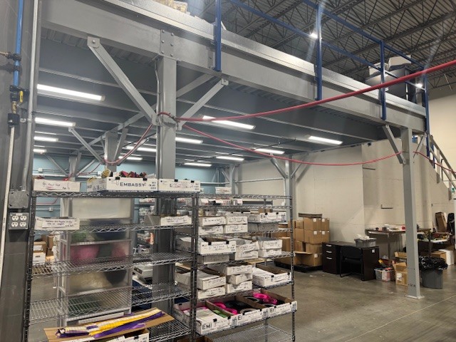Upper mezzanine deck surface showing perimeter safety railings and open industrial bay